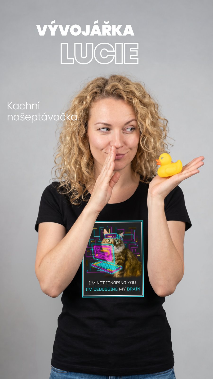Vývojářka Lucie v tričku Makak Debugger šeptá gumový kachničce